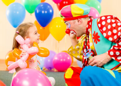 happy child girl and clown playing on birthday party
